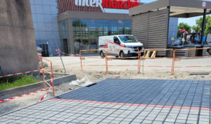 Pose de dalles drainantes alvéolaires sur parking de supermarché en cours de chantier — solution perméable Ocity PAV65 Nidaplast