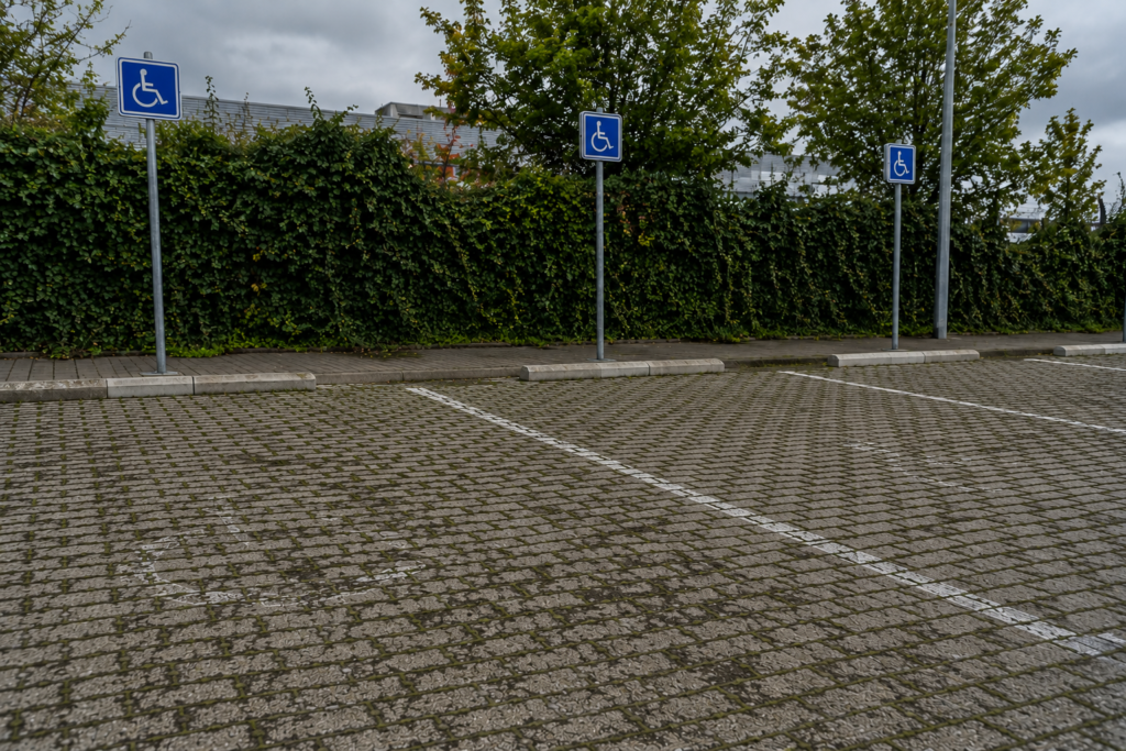 Places de stationnement PMR en pavés drainants dégradés avec panneaux réglementaires bleus — parking perméable accessible